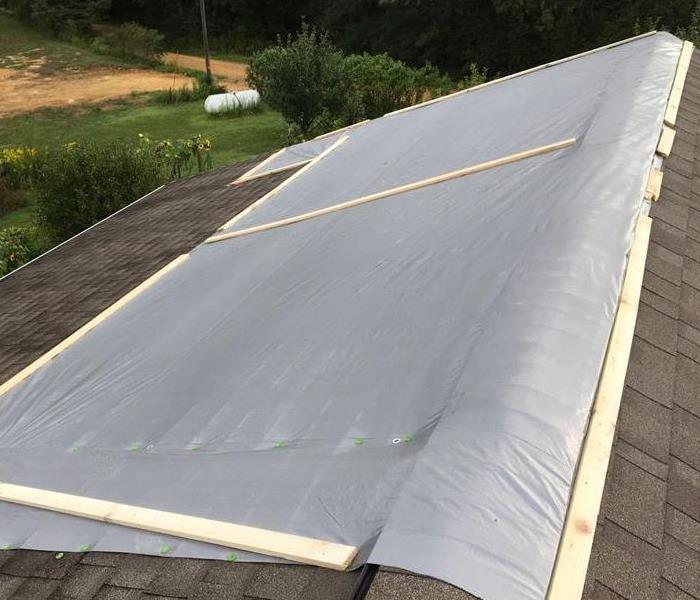 Roof with grey tarp and firing strips placed on roof