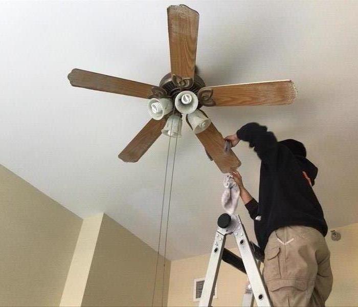 crew member cleaning ceiling fan