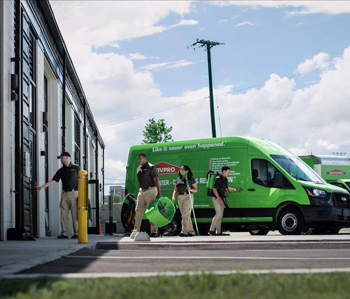 SERVPRO transit with 4 technicians carrying equipment.