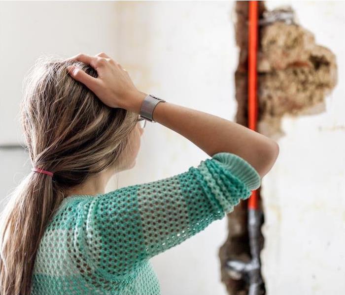  "a person in distress looking at a wall where water damage has occurred ”
